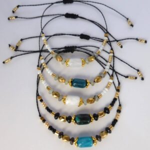 Bracelet Lindo avec perles en pierre naturelle gemme, perles en hématite doré et perles de rocaille noire. Les perles sont montées sur un cordon ciré terminé par des perles de rocaille dorées.