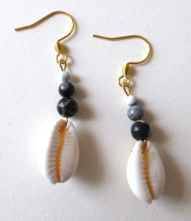 Boucles d'oreilles Kaura avec coquillage cauri, jaspe gris et crochet en acier inoxydable doré. Vue à plat.