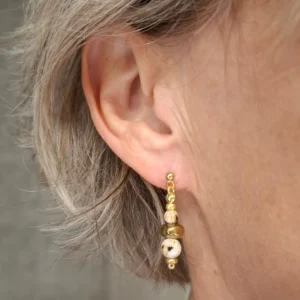 Boucles d'oreilles Marama en perles de nacre et hématite doré montées sur clou en acier inoxydable. Vue portées.