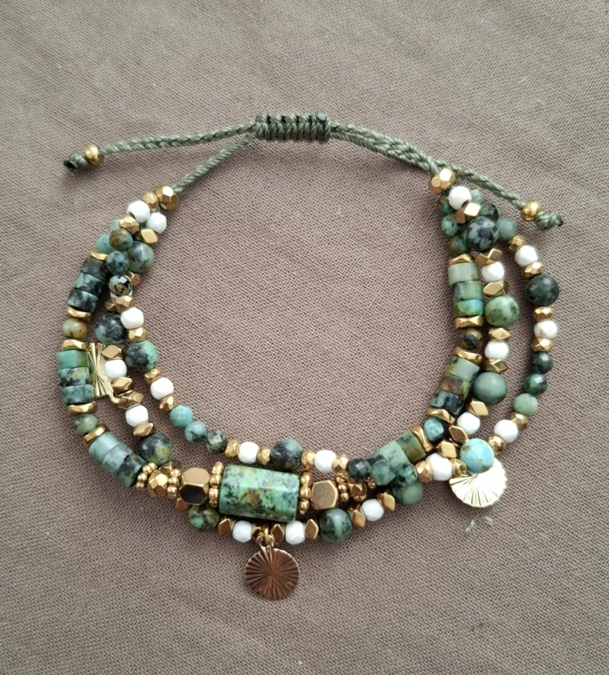 Bracelet Marama en perles de turquoise africaine, hématite doré et howlite avec pampilles dorées. Vue en O.