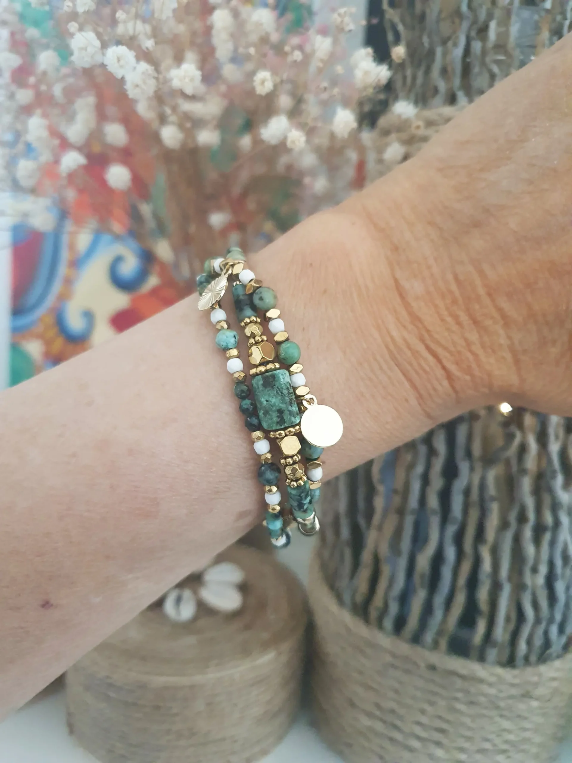 Bracelet Marama en perles de turquoise africaine, hématite doré et howlite avec pampilles dorées. Vue porté.