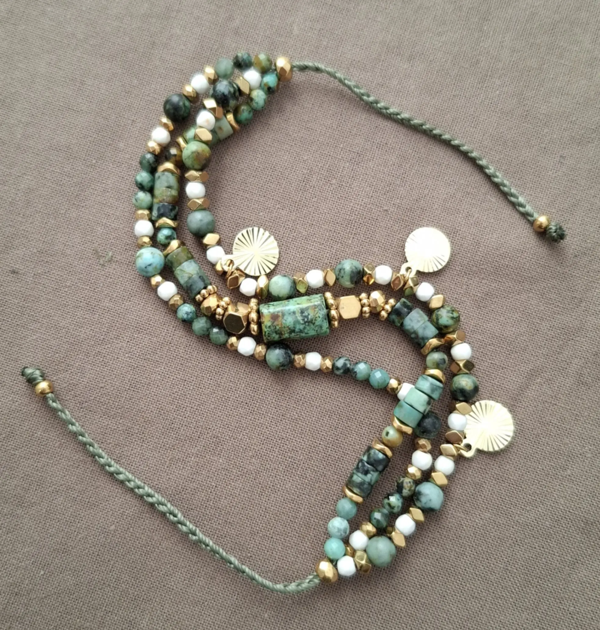 Bracelet Marama en perles de turquoise africaine, hématite doré et howlite avec pampilles dorées. Vue en S.